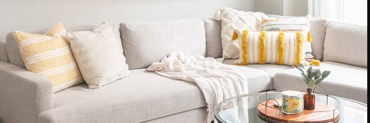 yellow striped and knitted bolster pillows on a light cream sofa