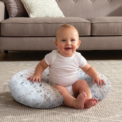 a baby boy is sitting using a boppy pillow for back support