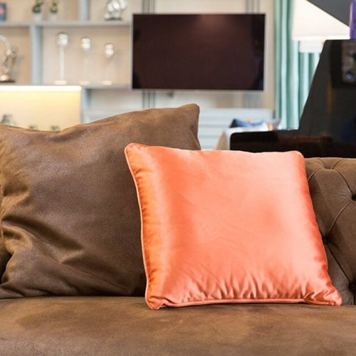 a peach throw pillow on a brown velvet sofa