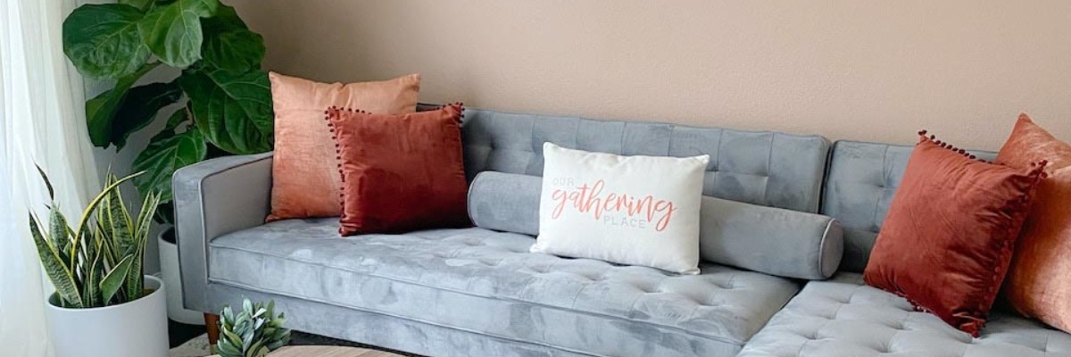 orange velvet square pillows and bolsters on a gray sofa